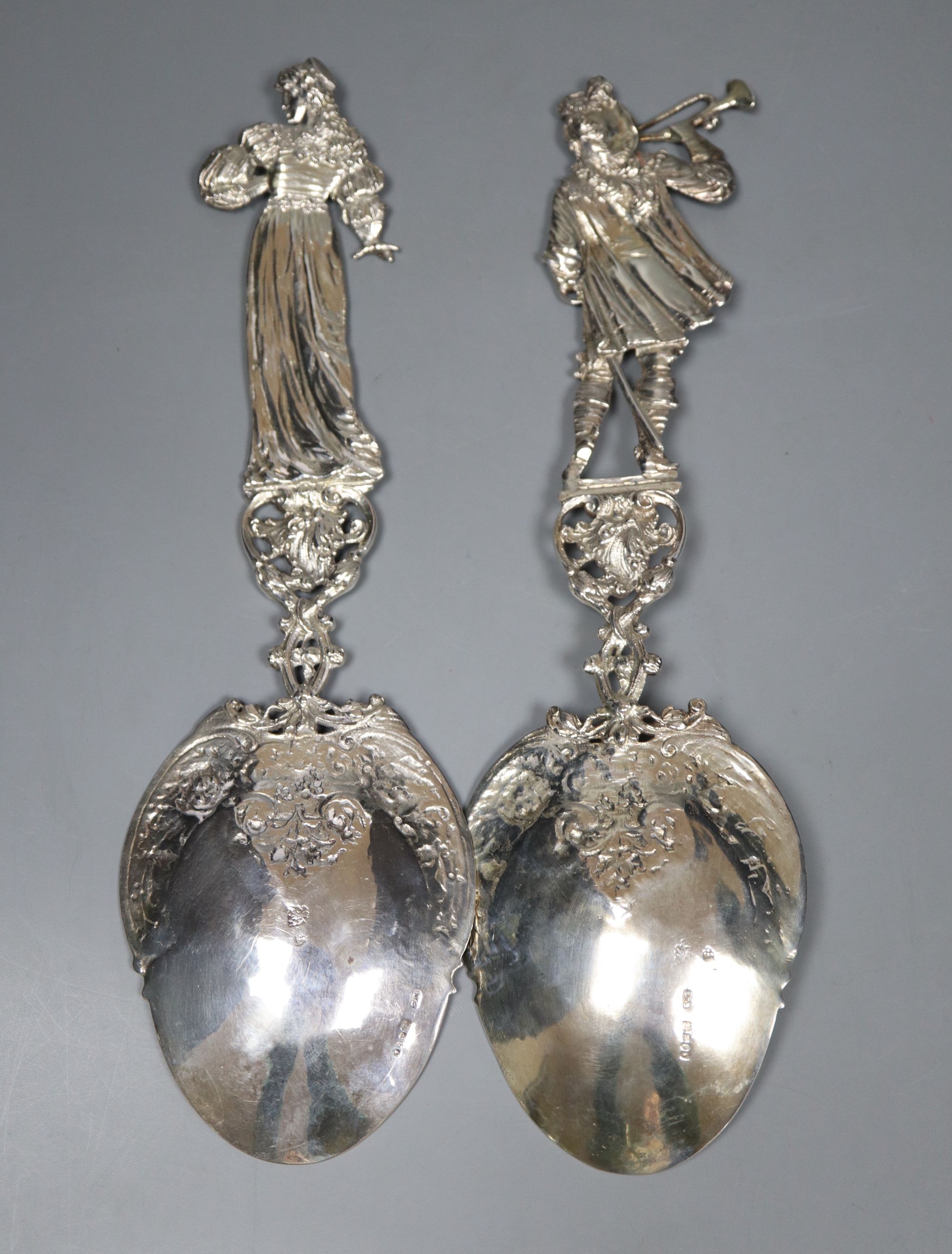 An ornate pair of late Victorian Hanau silver servers with figural handles, modelled as a lady and musician,